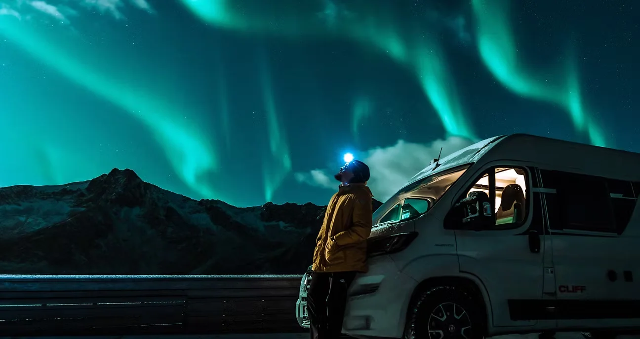 En reisende ved bobilen under nordlyset. Prosjektbilde fra Nortrip.